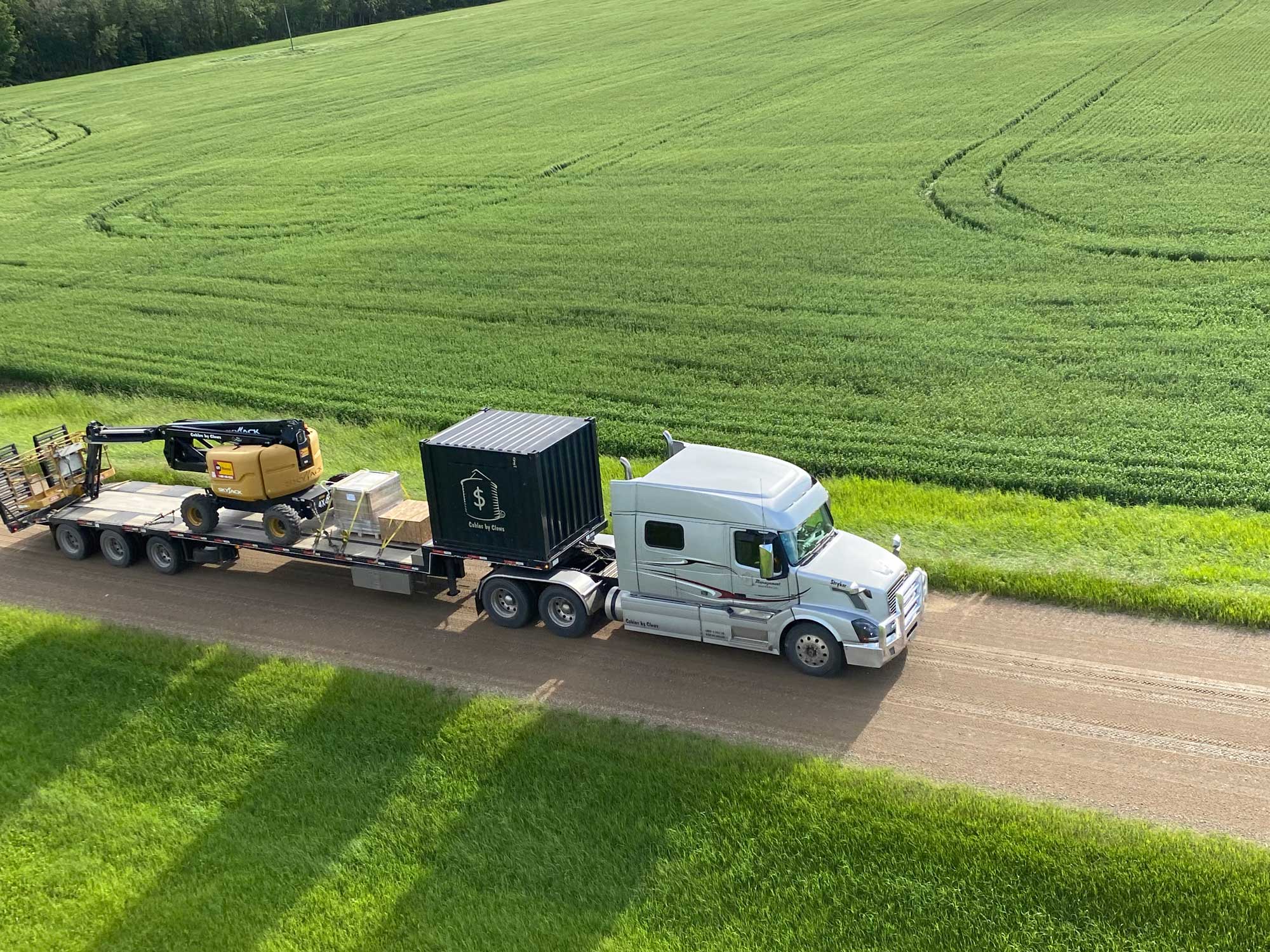 semi-truck on dirt road in green fields